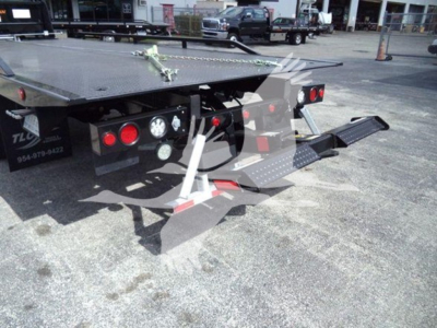 Flatbed tow truck rear with ramps extended and taillights visible.