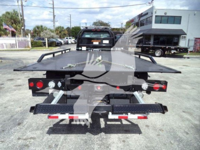 Tow truck rollback flatbed rear view showing hydraulic ramp bed and taillights with bumper and chrome hitch attachments.