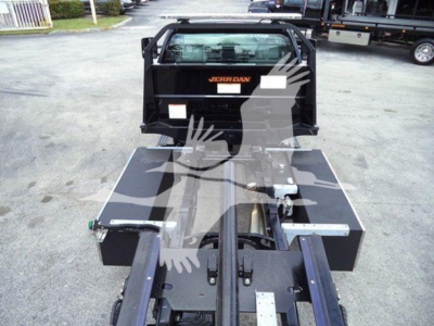 Truck rollback flatbed with black metal frame and hydraulic components, viewed from rear, showing loader and hitch area.