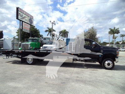 International CV truck with rollback bed in black, side view showing flatbed and wheel configuration.