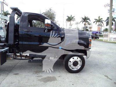 Truck cab side view of a 2023 International CV rollback truck with black paint and chrome wheel, VIN 1HTKTSWK6PH441635 visible, dealership lot background.