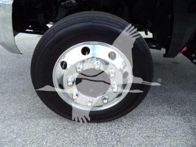 Truck wheel with polished rim and tire, front axle view in a rollback truck, chrome hub with bolts visible