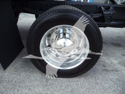 Wheel and tire on a rollback truck showing chrome hubcap and black tire tread.