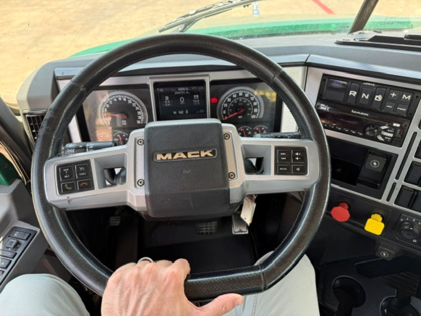 Steering wheel and dashboard of a Mack ANTHEM truck cab showing instrument cluster, steering wheels, and gear selector area.