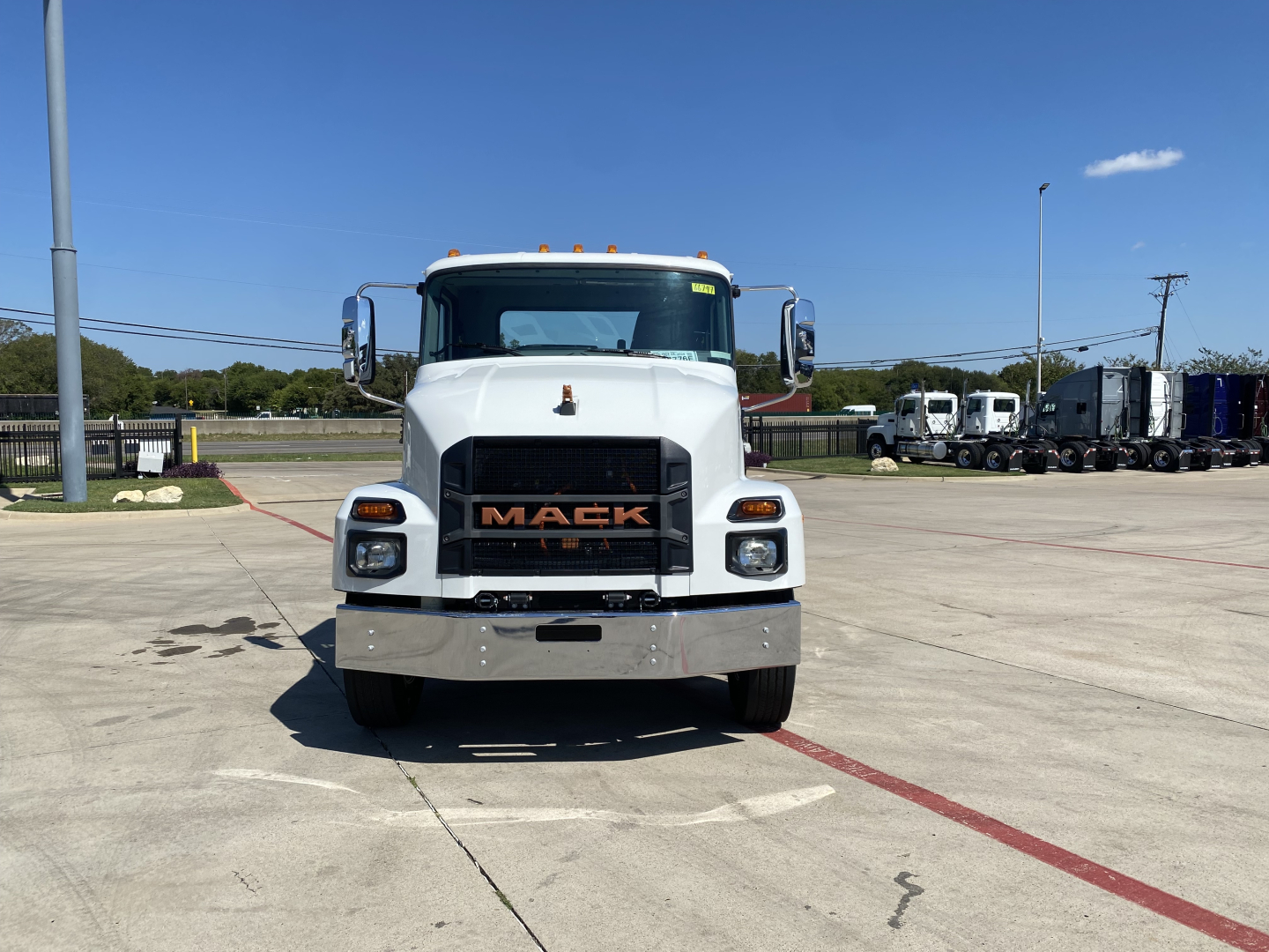 Front view of white 2024 Mack MD6 E cab and chassis truck with orange Mack logo grille.