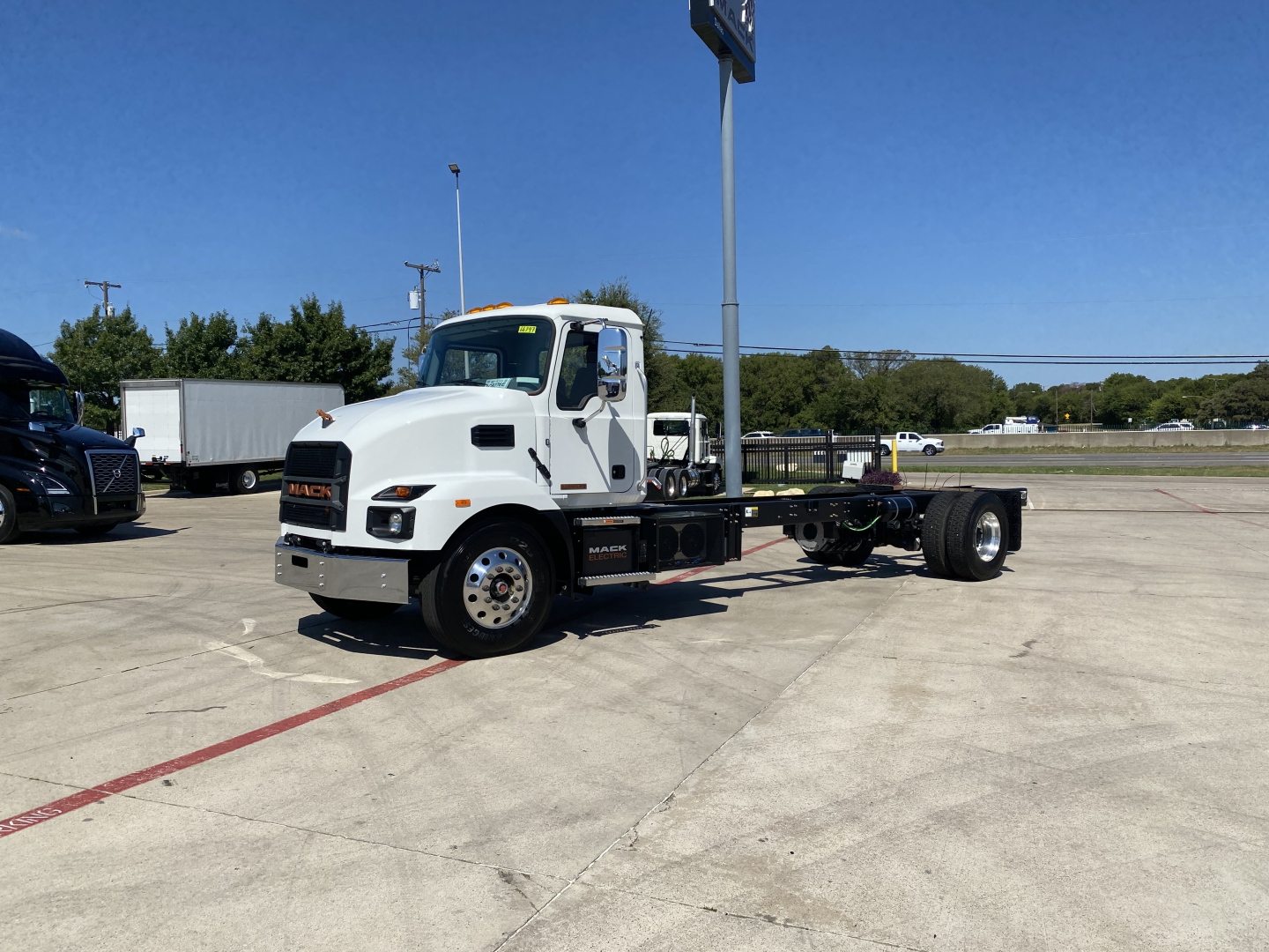 Cab and chassis truck showing white Mack MD6 frame and front wheel area with chassis rails visible and blank rear axle area, no freight cab.