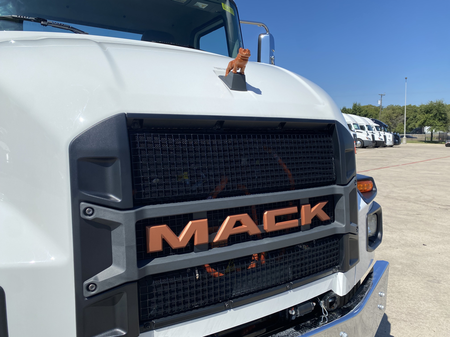Mack MD6 E truck front grille with orange MACK emblem in center and large windshield, cab and chassis view.