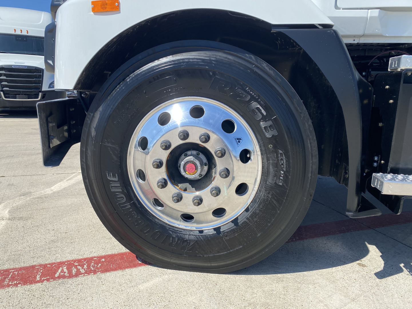 Mack MD6 E cab and chassis front wheel close-up showing polished steel wheel with multiple lug nuts and black tire labeled ‘TURBO’ and tire size details.