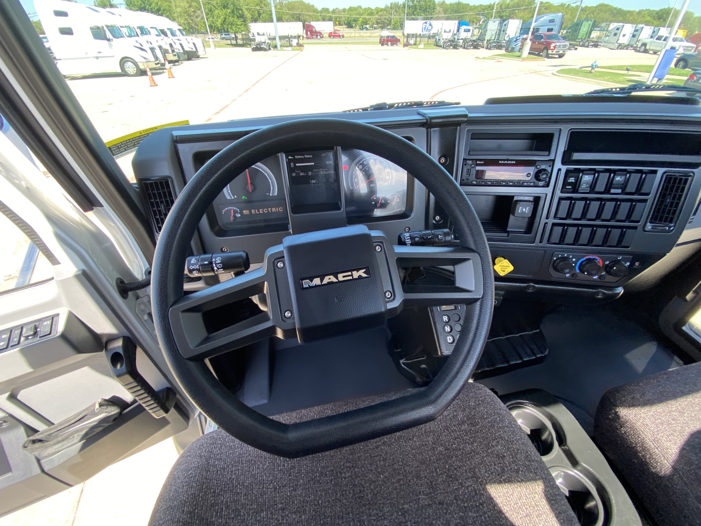 Cab interior of 2024 Mack MD6 E showing steering wheel with MACK logo, dashboard gauges, and central control panel.