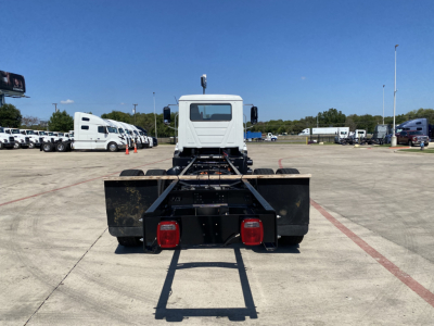 MD6 cab and chassis rear view showing dual taillights and hitch frame with white cab in distance.