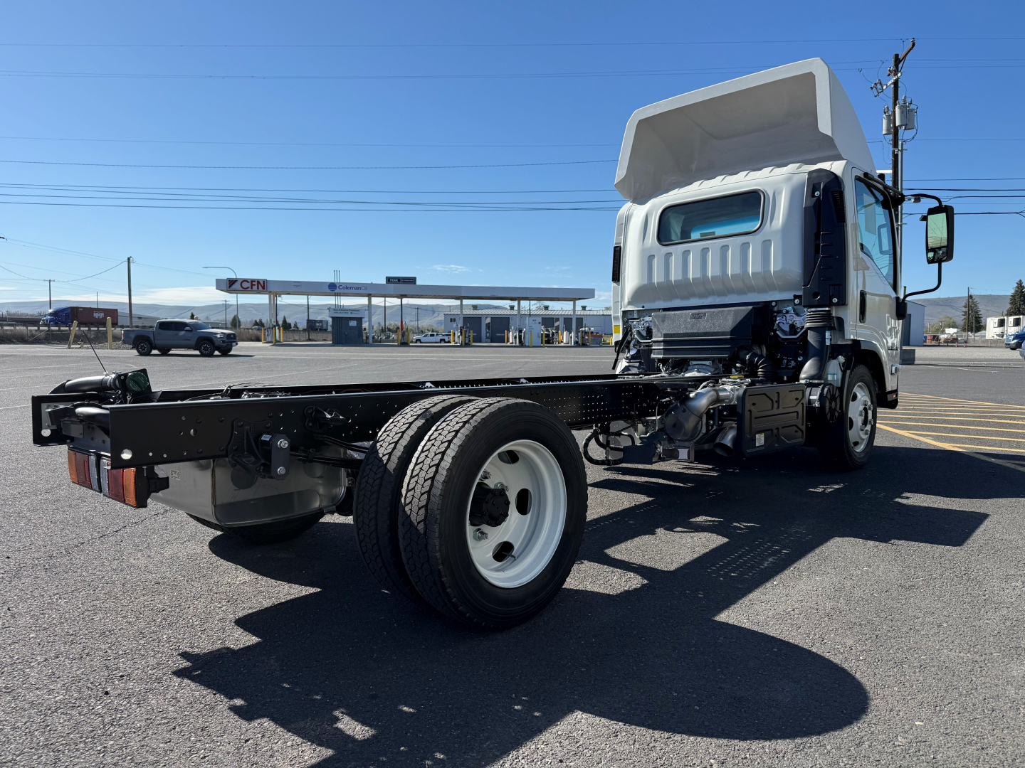 Isuzu NPRXD cab and chassis truck frame with cargo bed removed, front cab and open chassis showing drivetrain and single rear axle.