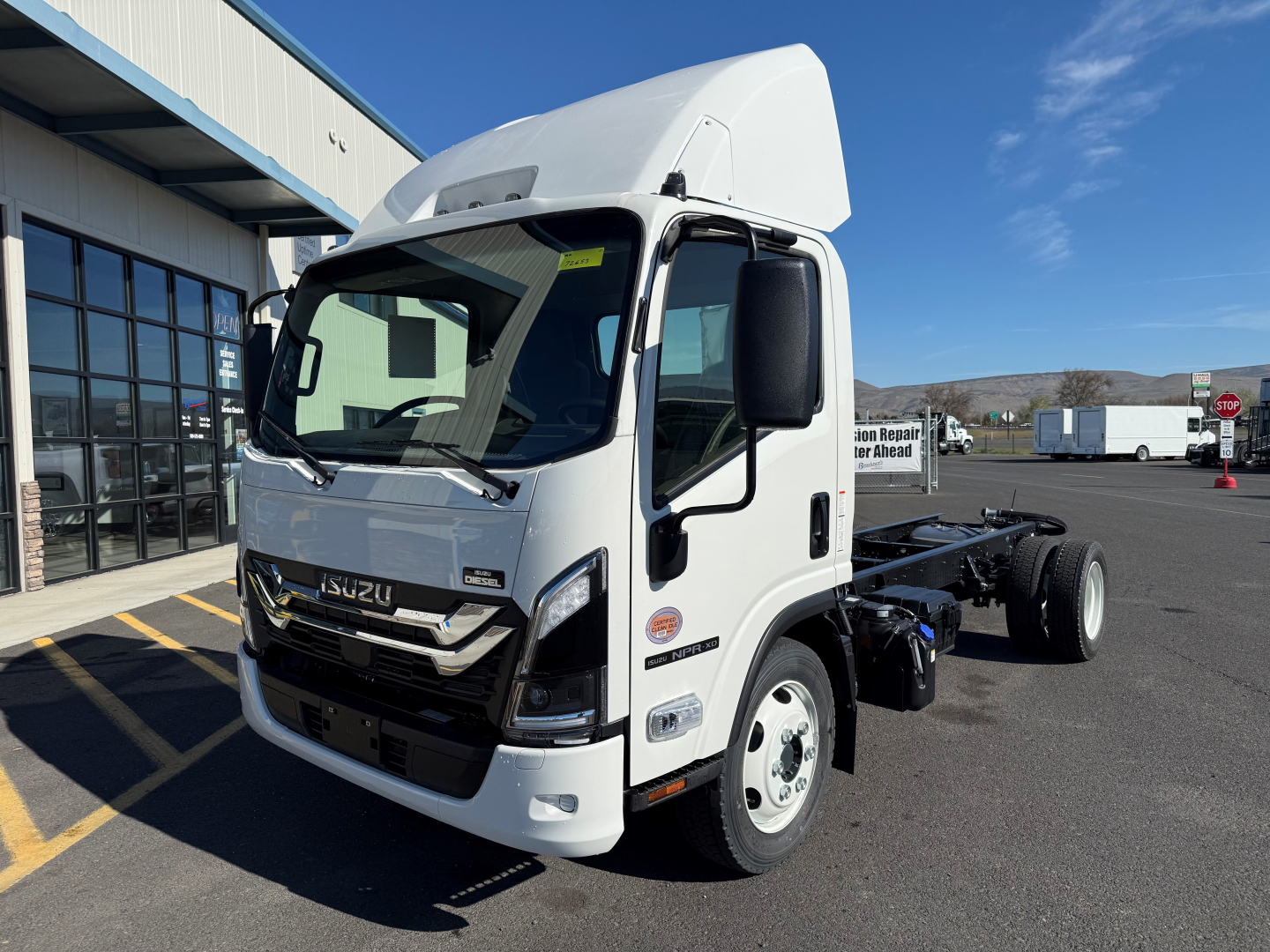 Isuzu NPRXD cab chassis truck in white showing front and driver side, with raised cab roof and chassis behind; no visible text on doors.
