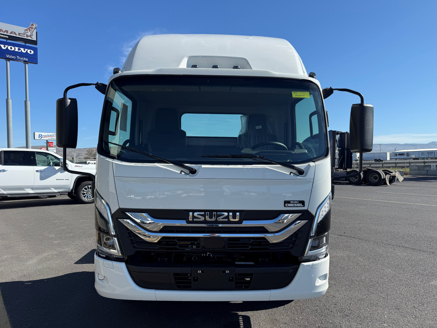 Isuzu NPRXD cab and chassis front view showing Isuzu emblem, grille, headlights, and large windshield.