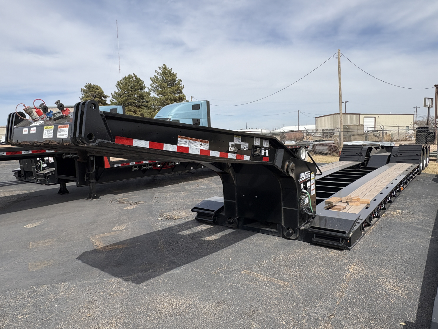 Load King 503/554 lowboy trailer with 9' deck and extended gooseneck, black-painted steel frame, reflective safety markings, and multiple axles.