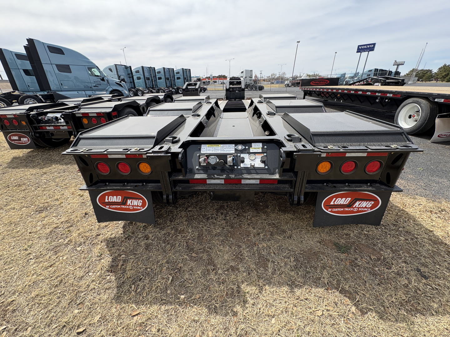 Load King trailer back view showing dual tandem lowboy deck sections, rear lighting, mud flaps with Load King logos, and hydraulic components in center