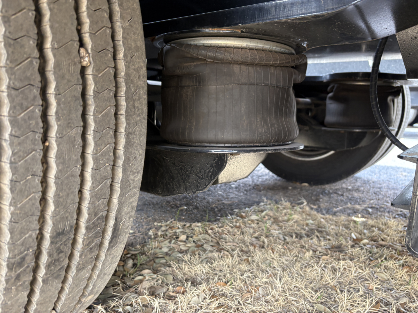 Load King trailer undercarriage showing air ride suspension/airbag and left rear dual tires with wheel, hydraulic lines visible.