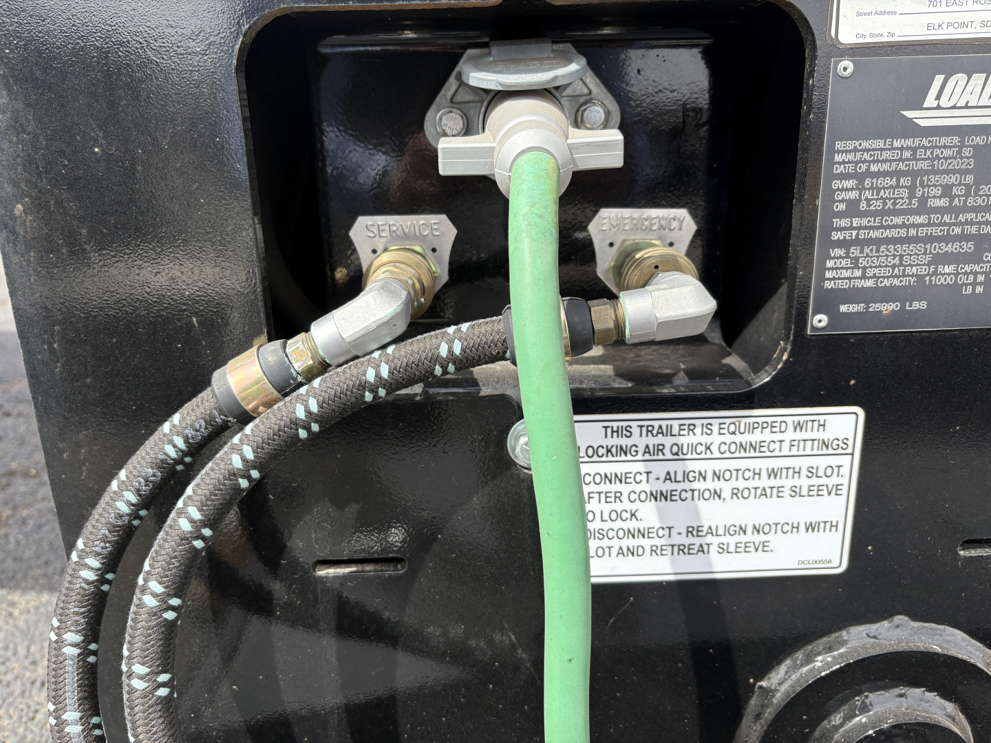 Trailer rear service connections with hoses and couplers labeled SERVICE and REPAIR, green ground hose connected, multiple hydraulic lines and fittings visible on Load King trailer.