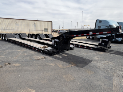 Load King trailer in lowboy configuration showing long flat deck with gooseneck and tandem axles, black finish, reflective markings