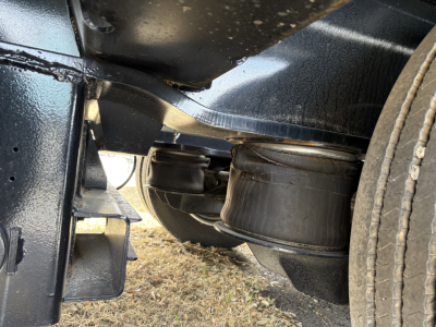 Trailer undercarriage showing suspension air bag and rear axle of a Load King lowboy trailer.