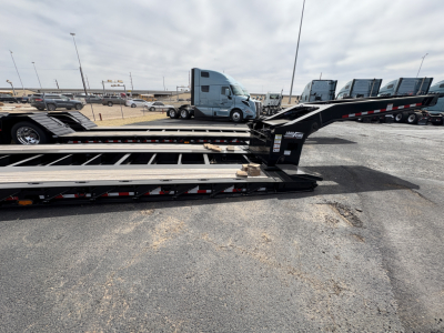 Load King trailer deck section with lowboy ramps and hitch, showing metal beams and warning decals.
