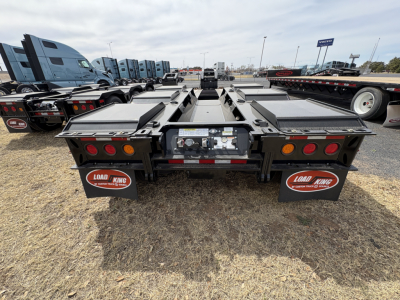 Load King trailer back view showing dual tandem lowboy deck sections, rear lighting, mud flaps with Load King logos, and hydraulic components in center