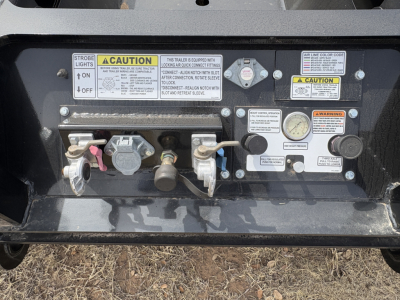 Trailer rear control panel showing strobe light switch, CAUTION labels, gauges, and valves on Load King lowboy trailer.