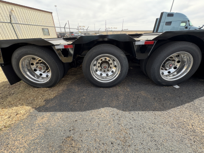 Load King trailer side view showing dual rear axles with chrome wheels and black frame
