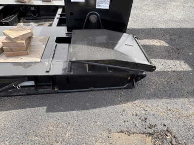 Load King trailer deck edge with hinged ramp section and black steel frame, 9' x 18' configuration, heavy-duty lowboy trailer component visible