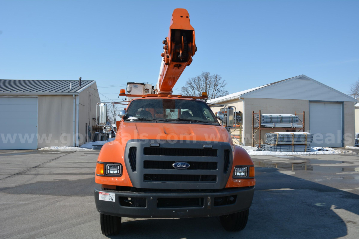 Ford F-750 bucket truck with mounted crane, front view in a lot.