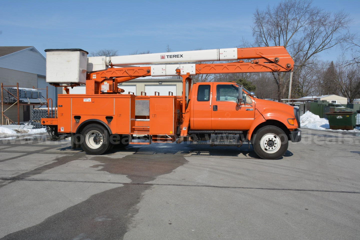 Ford F-750 bucket truck side view showing orange Terex boom lift and bucket, with cab, wheels, and storage compartments.