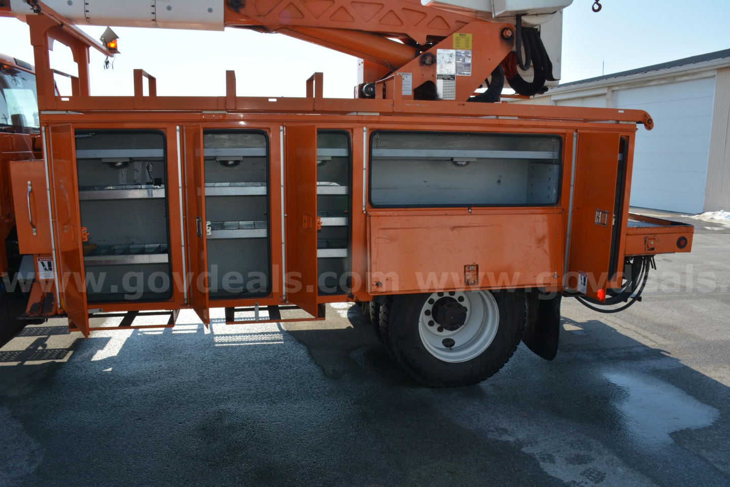 Ford F-750 service body with storage compartments, mounted on a bucket truck, side view showing multiple drawers and cabinet doors.