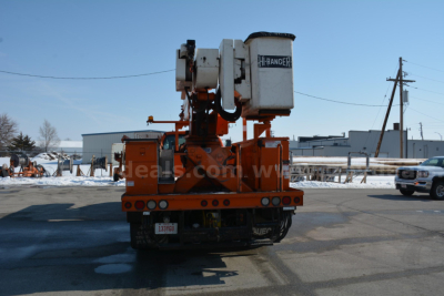 Rear view of an orange bucket truck with a mounted crane, Hi-Ranger bucket, and vehicle undercarriage visible.