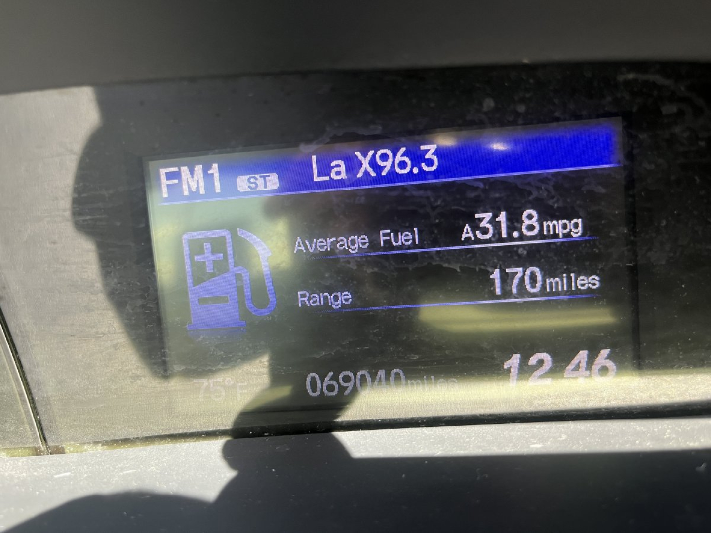 Car dashboard display showing fuel information: FM1 La X96.3, Average Fuel 31.8 mpg, Range 170 miles, plus generic icons.