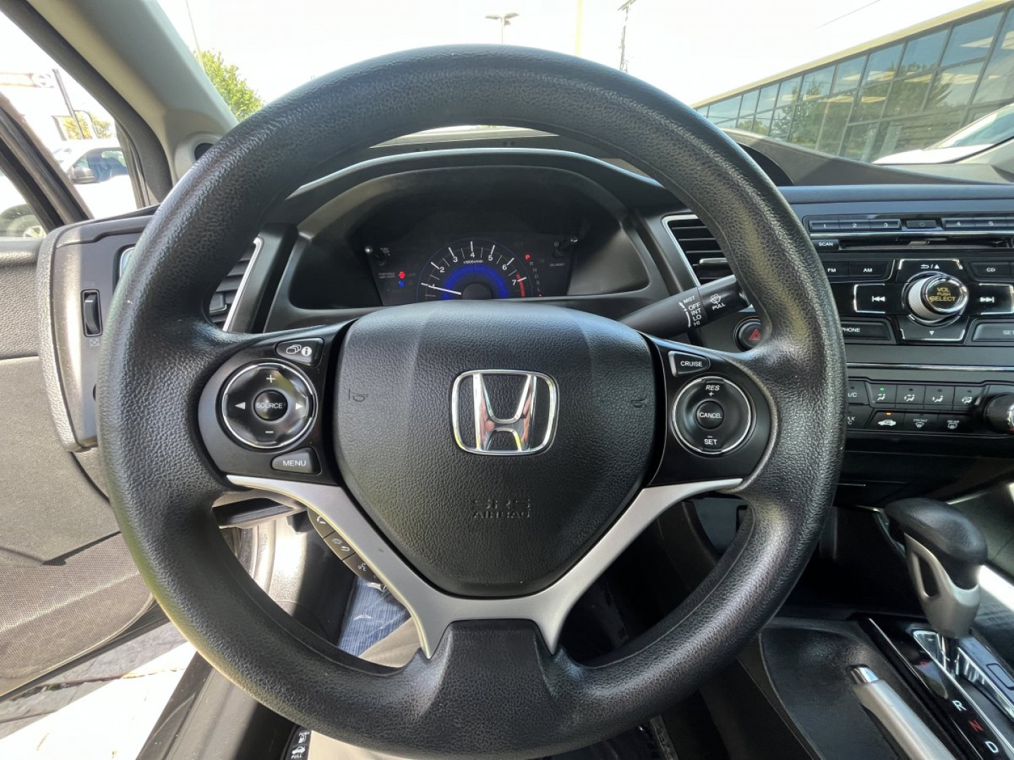 Honda Civic steering wheel and dashboard view in interior showing steering wheel controls and instrument cluster.