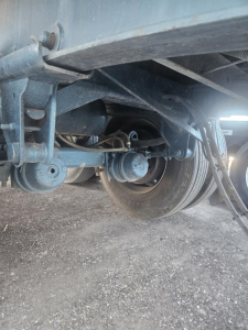 Trailer undercarriage view showing suspension and axle components of a Fruehauf steel flatbed trailer.