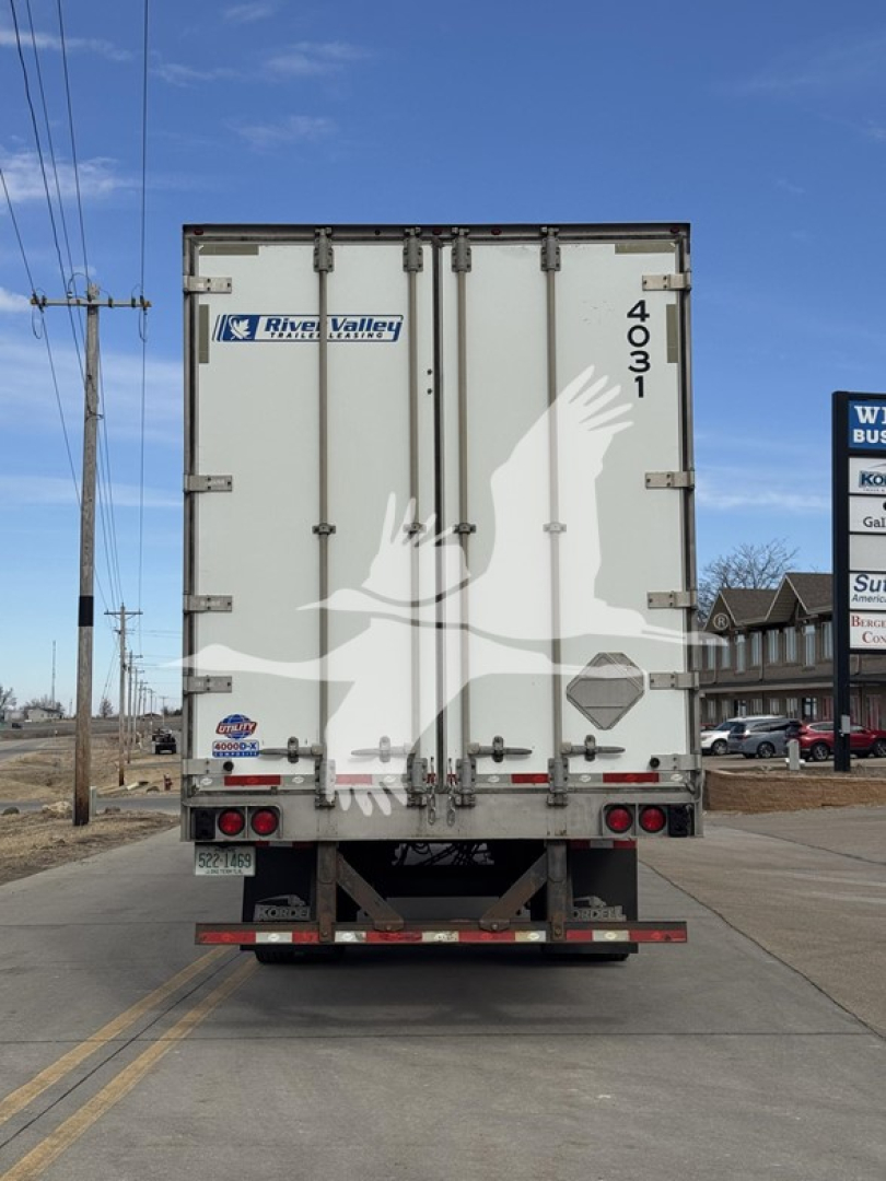 Trailer rear view showing River Valley logo, doors with overhead latches, '4031' on right edge, red/amber taillights and bumper under a blue sky.