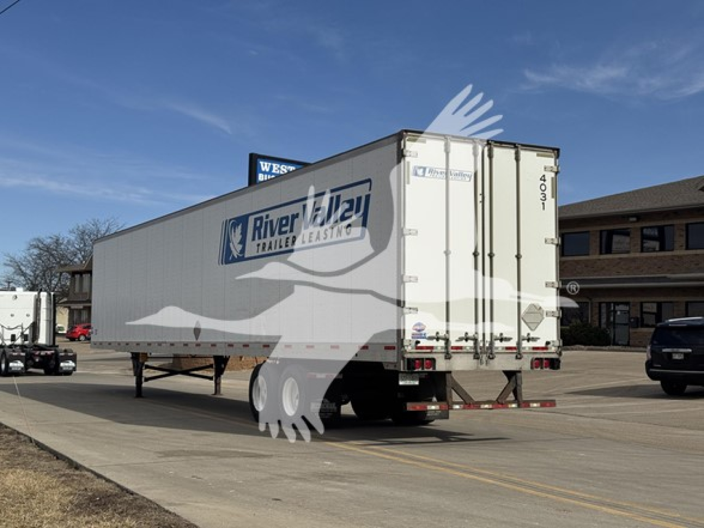 Trailer rear and side view of a used Riverway Trailers 4000Dx box trailer with white doors, Riverway logo, and rear doors.