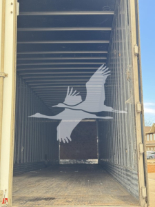 Trailer interior showing empty cargo space with metal ribbed walls and ceiling; watermark of a flying bird overlay in center.