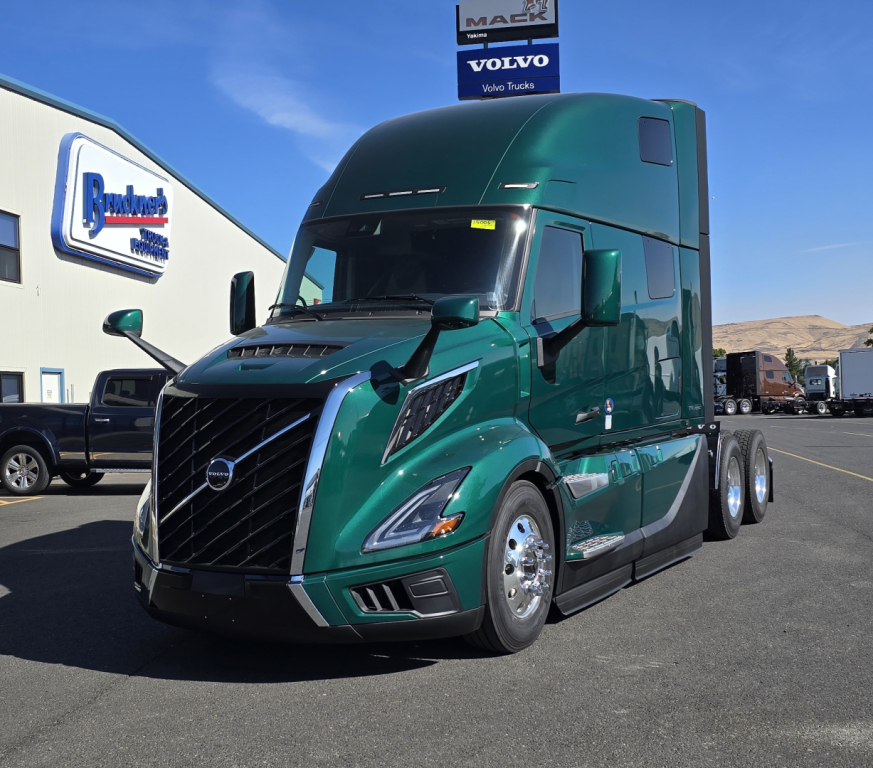 Volvo VNL64T860 truck in green shows aerodynamic cab and dual rear axles.