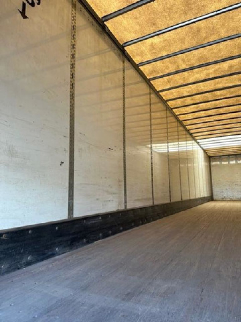 Interior of a trailer with wooden floor and side walls, empty trailer cabin; no legible labels visible.