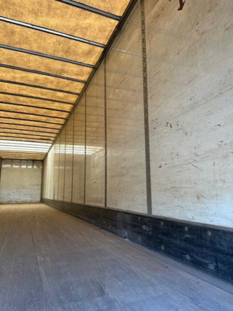 Trailer interior showing empty cargo area with wooden ceiling slats and aluminum side walls; long length perspective.