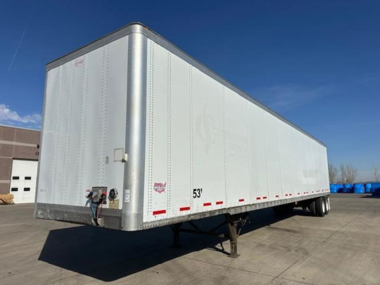 Trailer side view showing a 53-foot white Wabash van trailer with dual rear axles and landing gear in a dealership lot.