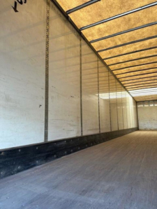 Interior of a trailer with wooden floor and side walls, empty trailer cabin; no legible labels visible.