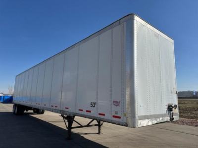 Trailer side view showing a 53' silver Wabash van trailer with tandem hitch and landing gear, plain riveted aluminum exterior.
