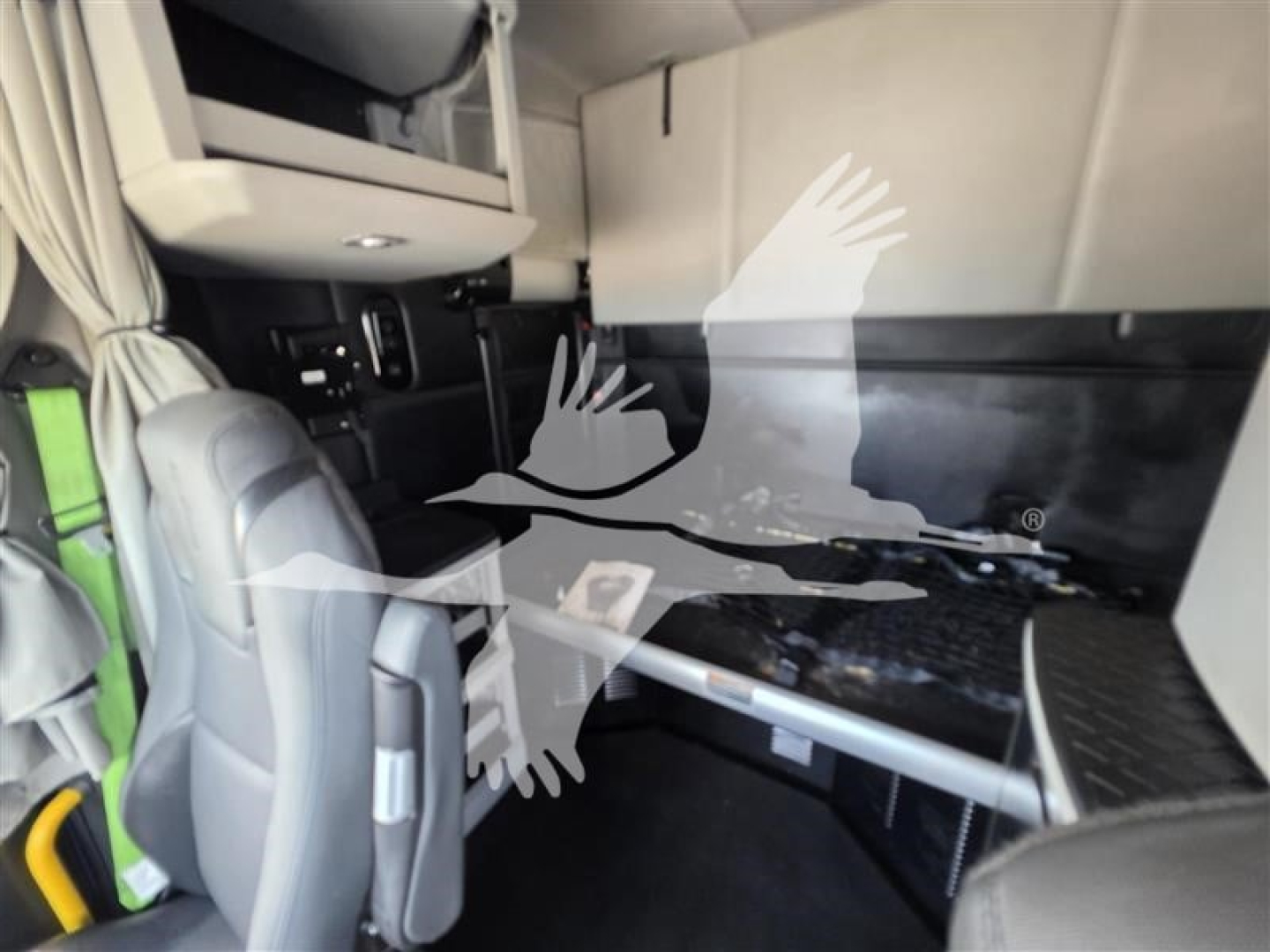 Cab interior of a 2023 Kenworth T680 sleeper showing driver seat, dashboard area, and bunk with storage shelves; no readable text visible.