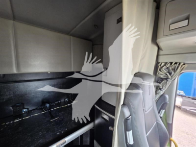 Cab interior of a 2023 Kenworth T680 showing sleeper cabin with storage cabinet and partition wall.