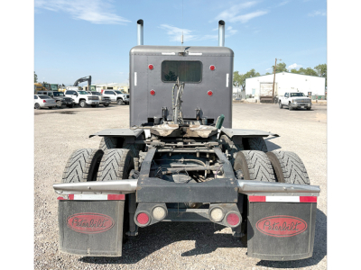 Peterbilt 389 extended hood tractor rear view showing dual rear axles, mudflaps with Peterbilt logos, and rear hitch area.