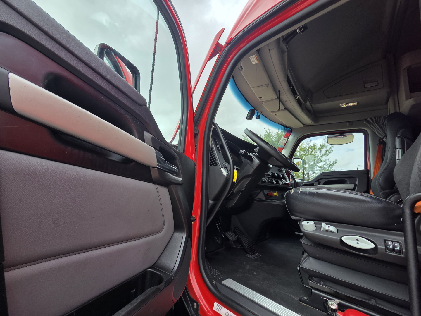 Kenworth T680 cab interior showing driver seat and dashboard in view from open door