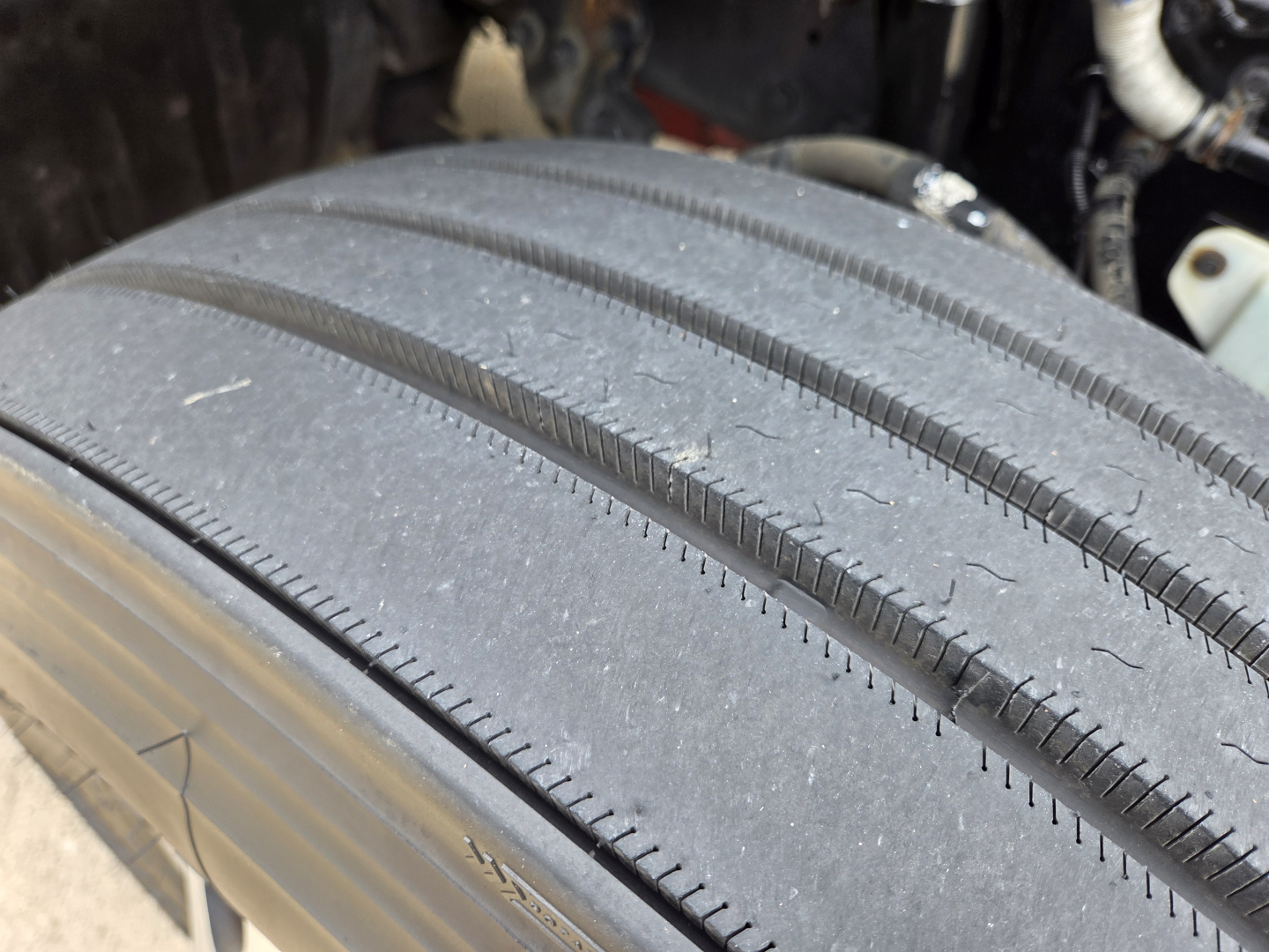 Kenworth T680 wheel/tire close-up showing tread and sidewall, part of front axle area.