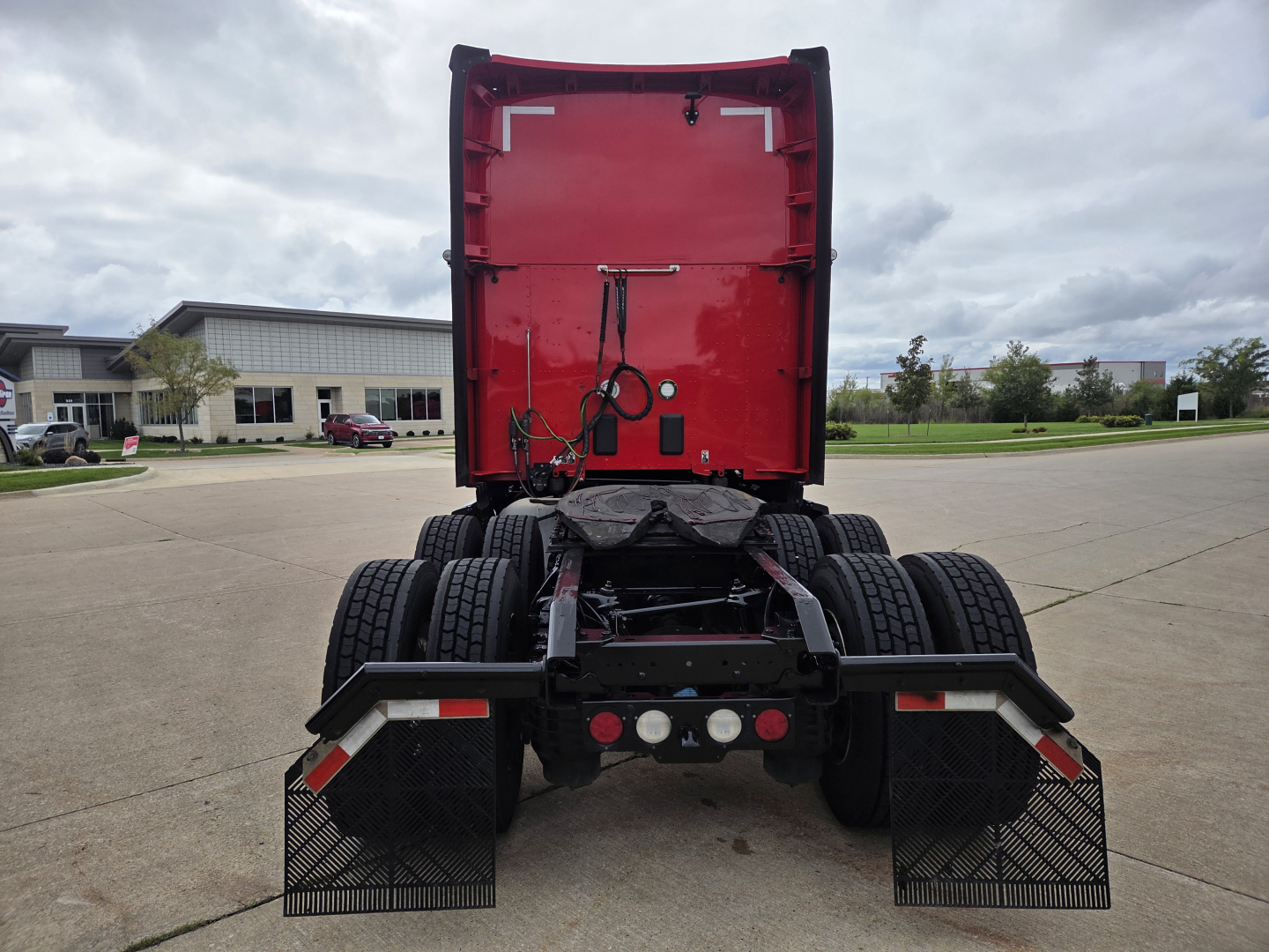 Kenworth T680 truck rear view showing fifth wheel, dual rear axles, mudflaps, and warning lights.